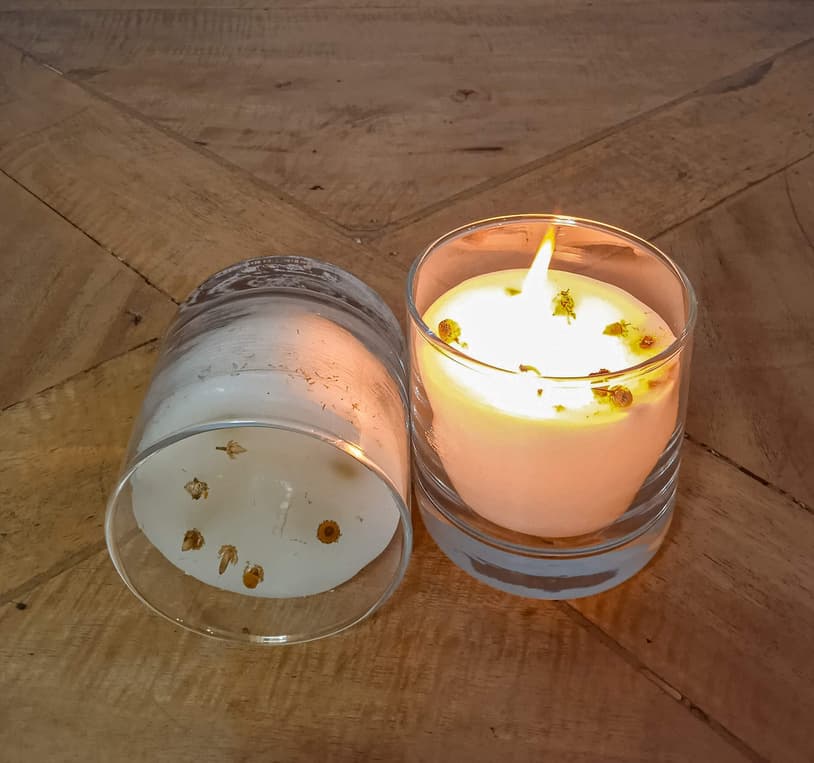 A hand-poured candle glowing softly on warm wood